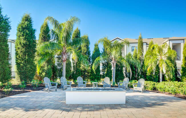 an outdoor patio with palm trees and chairs and a fountain