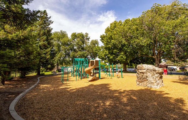 a playground with a slide and trees in a park at Avenue Two Apartments, Redwood City  , CA