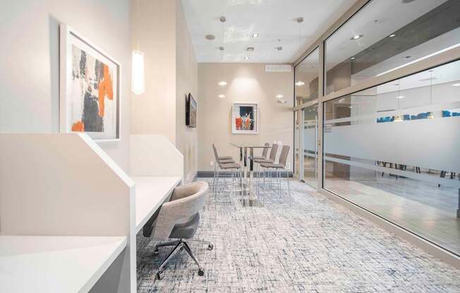 A modern office space with a glass wall and a grey carpet.