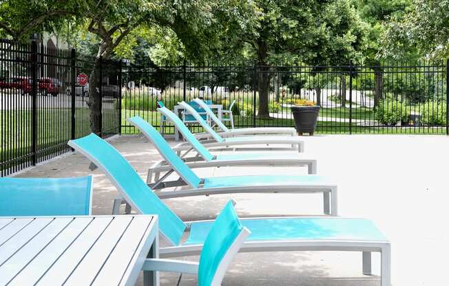 A row of blue and white chairs are lined up on a concrete patio.