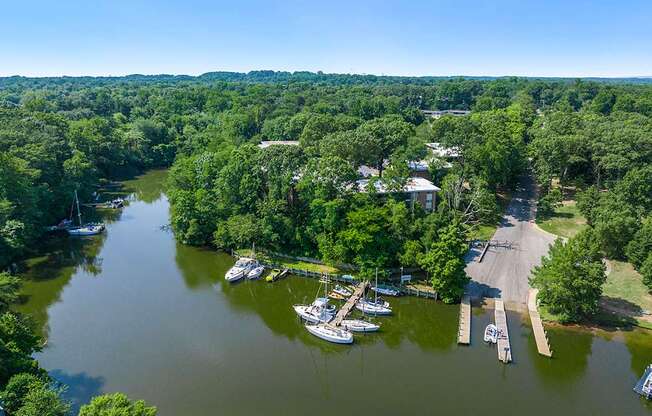 A serene lake surrounded by lush greenery and a dock with boats.