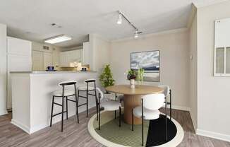 A kitchen with a bar and a dining table with chairs.