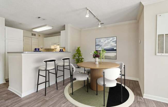 A kitchen with a bar and a dining table with chairs.