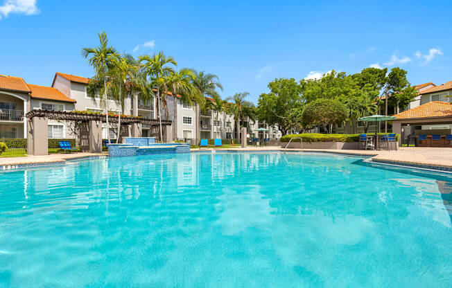 A large swimming pool in front of a building with a blue sky in the background.