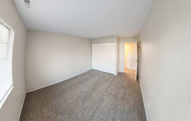 an empty bedroom with a carpeted floor and a door to a closet