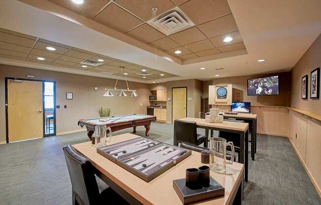 A conference room with a tables and chairs and a TV on the wall.