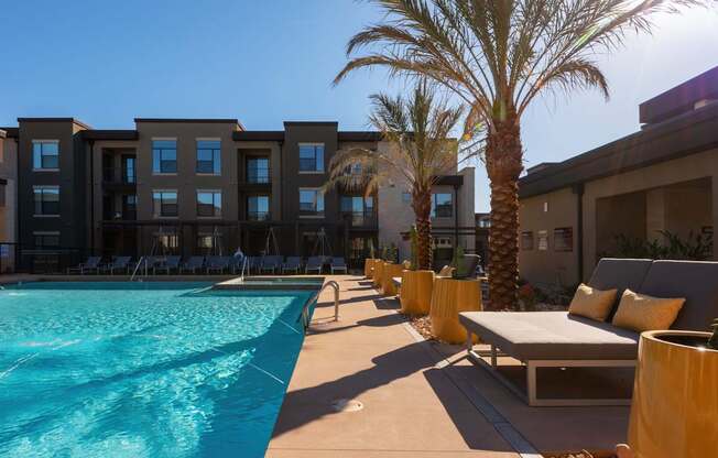 A pool area with sun loungers and palm trees.
