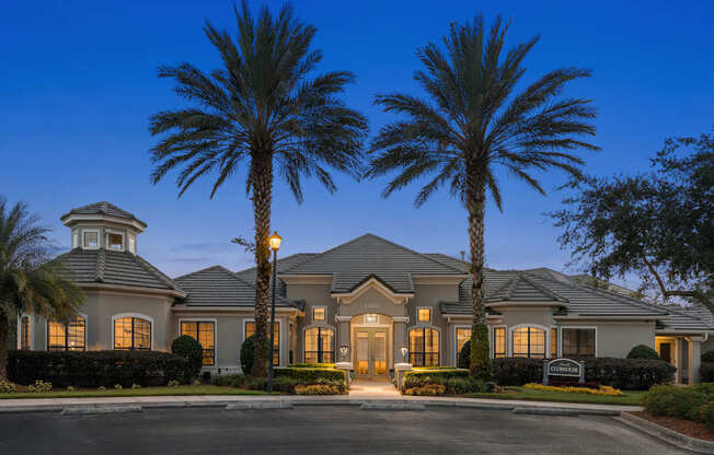 A large house with a tower and palm trees in front.