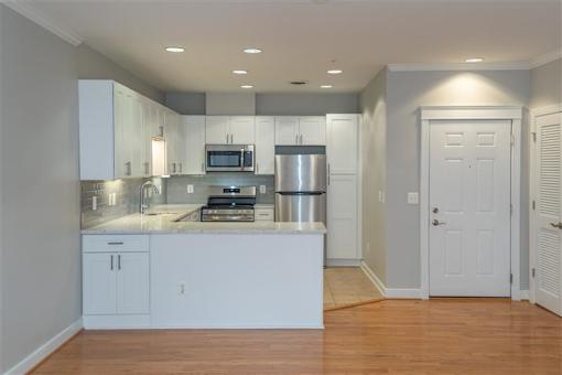 A kitchen with white cabinets and a stainless steel refrigerator.
