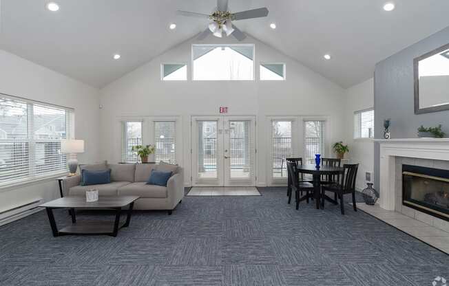 A living room with a grey carpet and a fireplace.