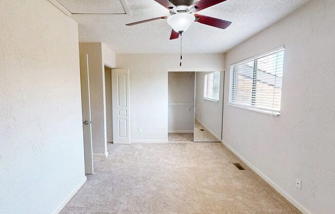 an empty living room with a ceiling fan and a closet