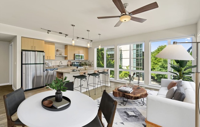 a living and dining area with a large window and a ceiling fan