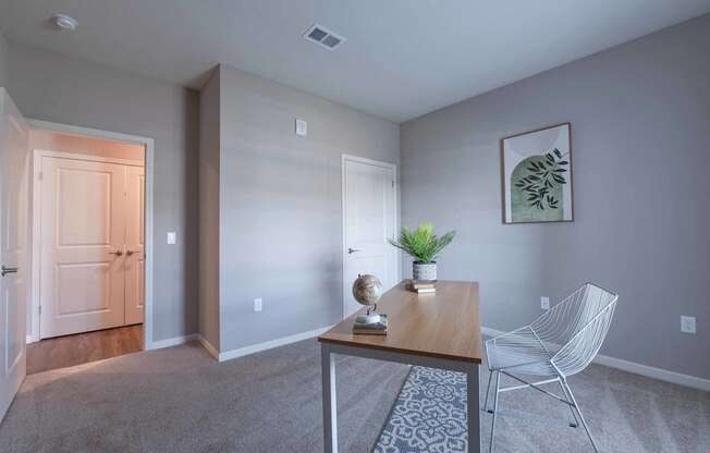 Adesk with a chair in a room with a door to a hallway at Crossing at Grove City apartments in Grove City, OH