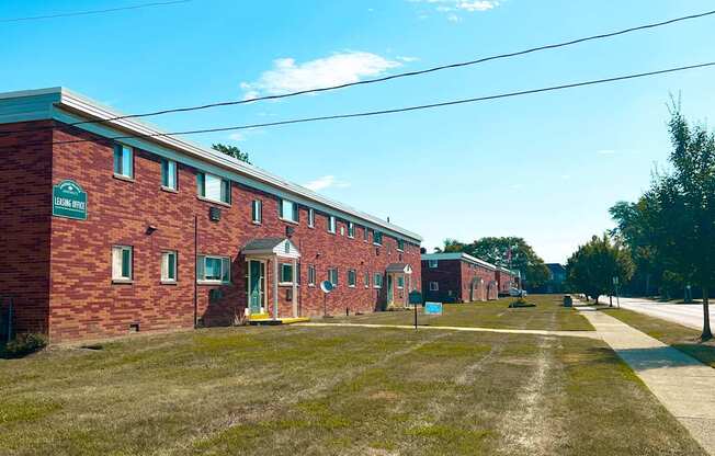 A long brick building with a green sign on the front.