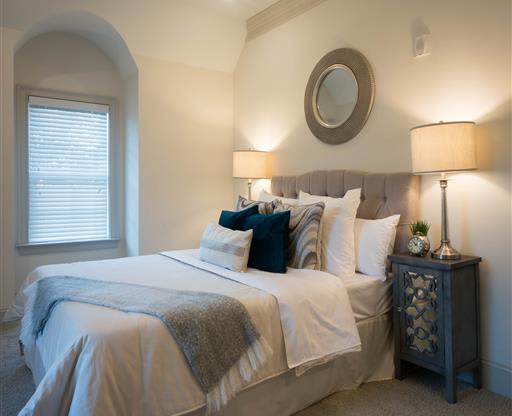 A serene bedroom featuring a tufted bed with layered pillows and soft lighting from bedside lamps.