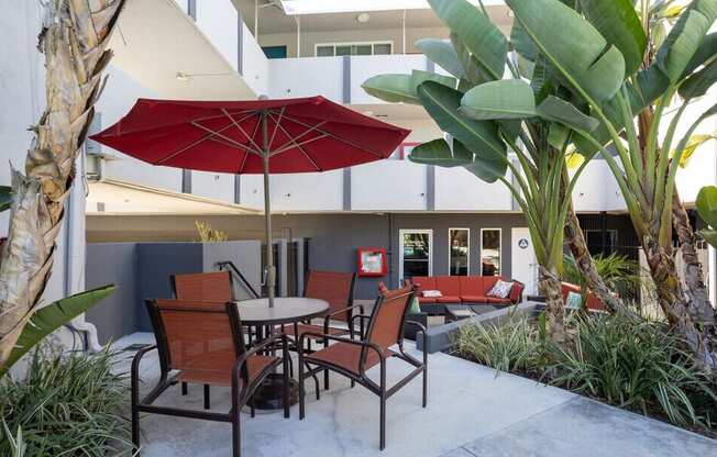 A patio with a table and chairs under a red umbrella.