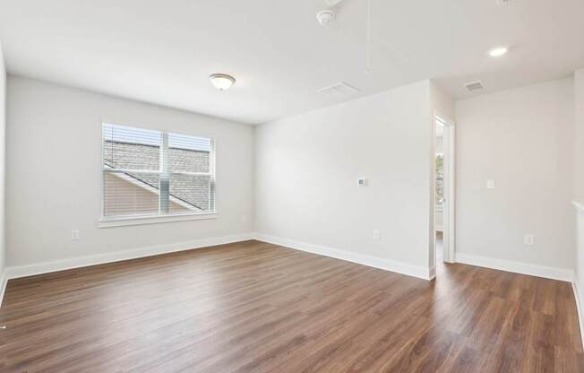 A room with wooden floors and a window with blinds.