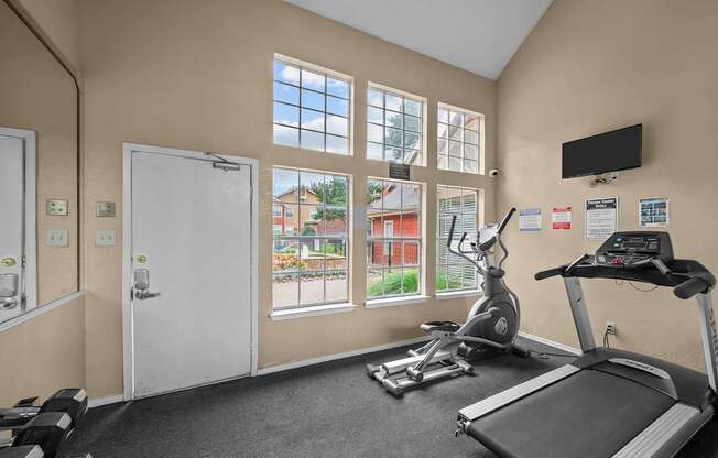 A gym room with a treadmill, exercise bike, and other equipment.
