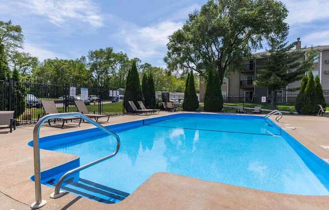 A blue swimming pool surrounded by trees and a fence.