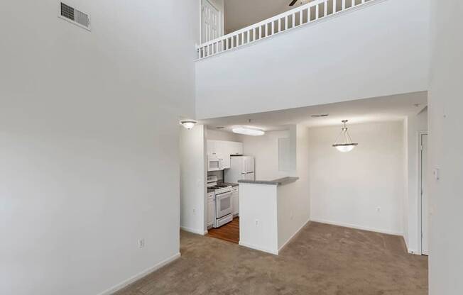 an empty living room and kitchen with a ceiling fan