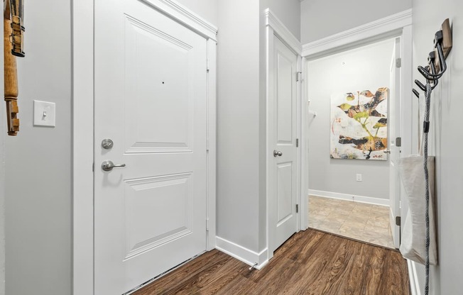 A hallway with a white door and a wooden floor.
