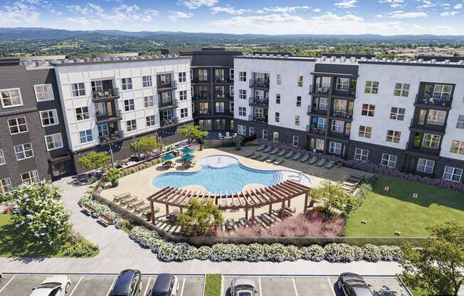 Two-Bedroom Apartments in Chattanooga, TN - Populus Waterside - Aerial View of Resort-Style Pool with Sun Shelf and Tanning Ledge, Lounge Seats, Pergola, Tables, Chairs, and Umbrellas.