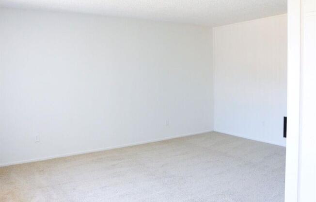 an empty room with white walls and carpet