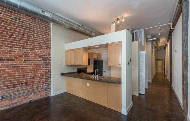 a kitchen with wooden cabinets and a brick wall at Mayton Transfer Lofts, Petersburg Virginia