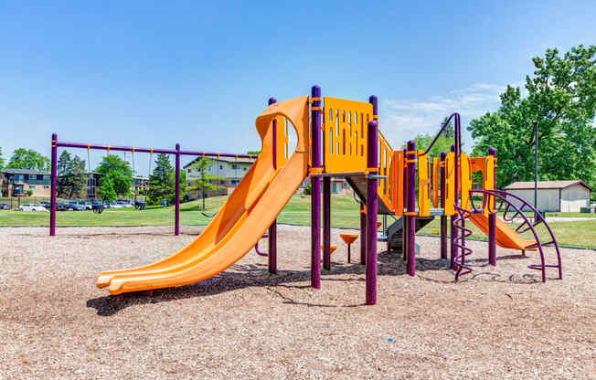 a playground with a yellow slide and other playground equipment at Willow Hill Apartments, Justice, IL