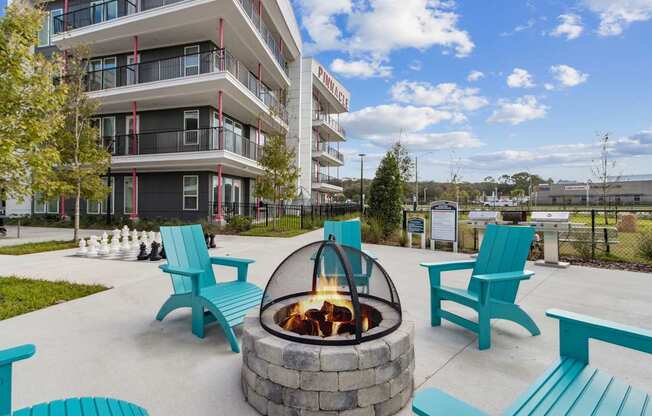 a fire pit with blue chairs in front of an apartment building