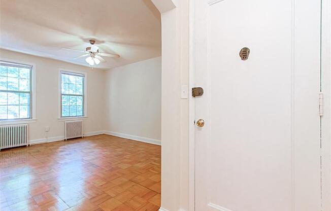 entrance to apartment unit with view of living area with large windows, ceiling fan and hardwood floors at 1400 van buren apartments in washington dc