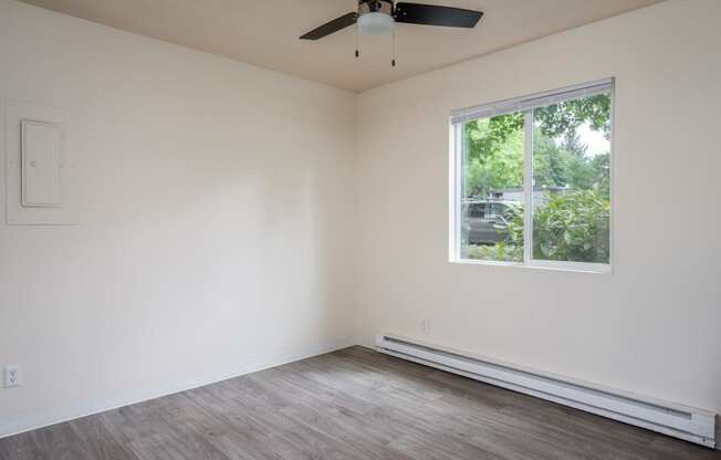 an empty bedroom with a ceiling fan and a large window