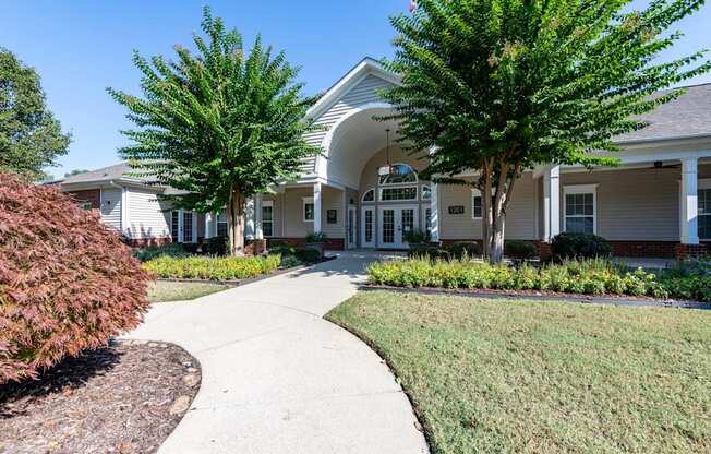A white building with a green tree in front.