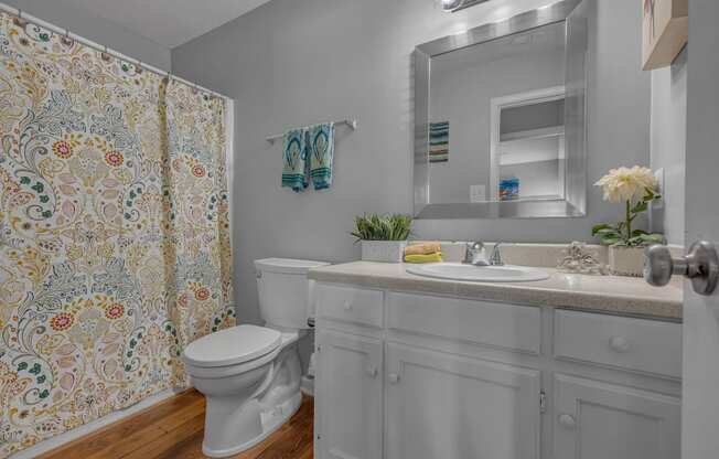 A white bathroom with a floral shower curtain.