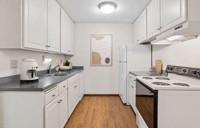A kitchen with white cabinets and a wooden floor.
