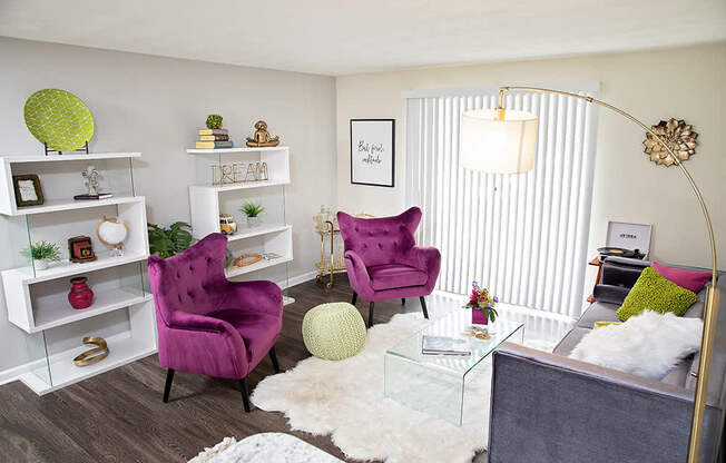 A living room with a purple chair and a glass table.