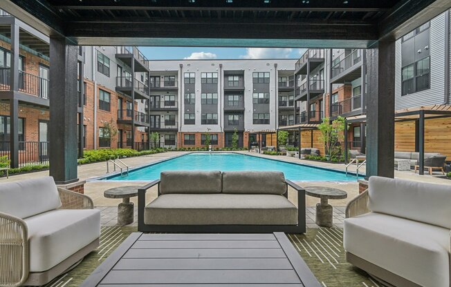 Elegant apartment complex featuring a luxurious pool and modern outdoor seating, perfect for relaxation and leisure.