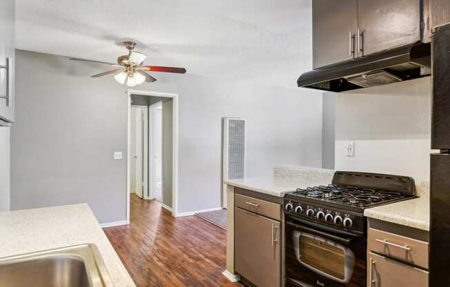 an empty kitchen with stainless steel appliances and a ceiling fan