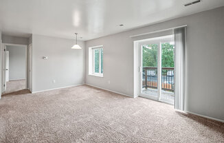 an empty living room with a sliding glass door to a balcony