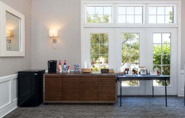 a bar in a room with large windows and a table with drinks on it