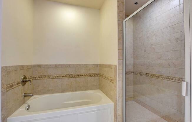 A white bathtub with a silver faucet is in a bathroom with tiled walls.