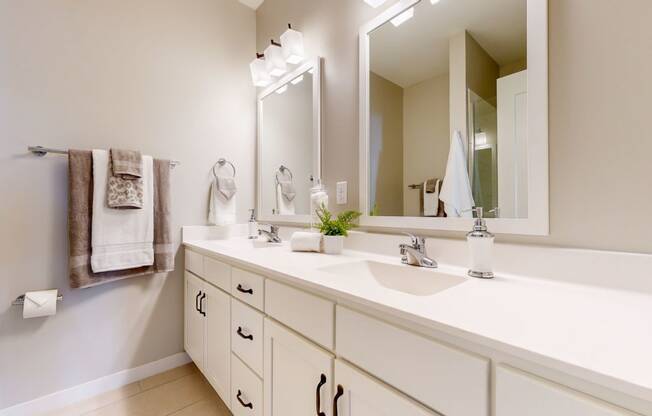 a white bathroom with two sinks and a mirror