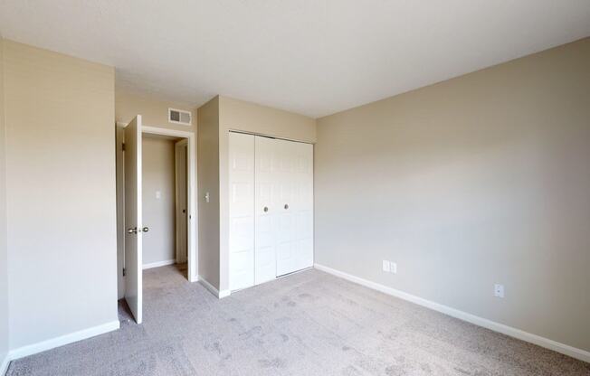 an empty bedroom with a closet and a door to a hallway