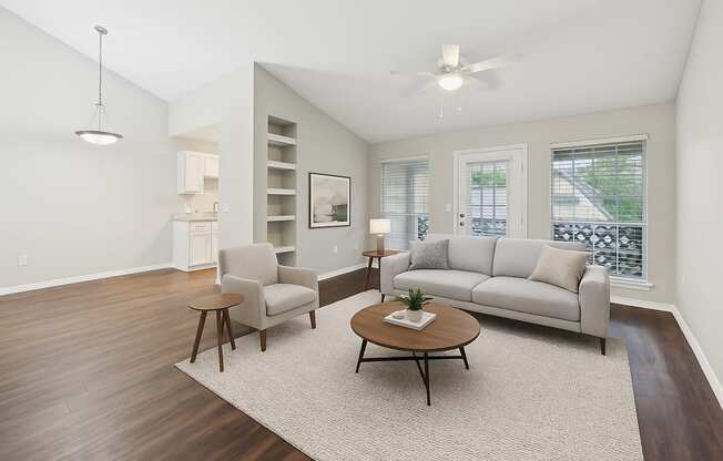 A living room with a grey couch, a chair, a coffee table, and a ceiling fan.