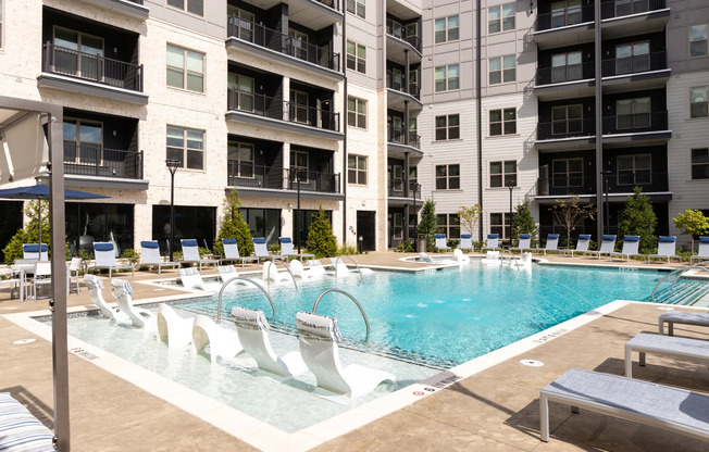 The pool area at our apartments in Atlanta, featuring pool chairs, beach chairs, and a view of the apartments.