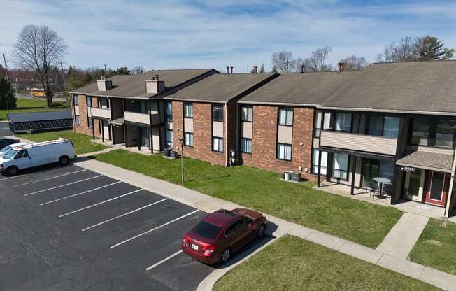 an apartment building with a red car parked in a parking lot