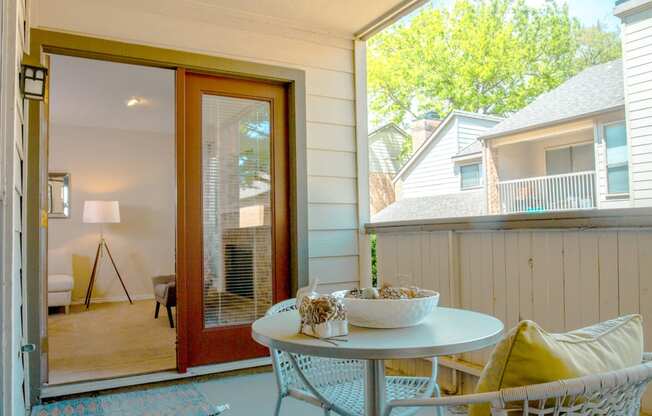 Model patio with a table and chairs and a window Chisholm Place Apartments in Plano, TX