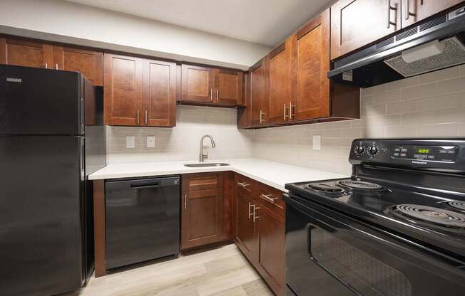 A kitchen with black appliances and wooden cabinets.