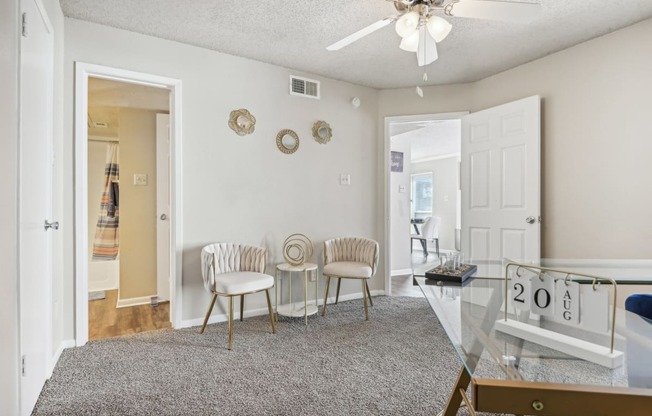 a living room with a glass table and chairs and a ceiling fan