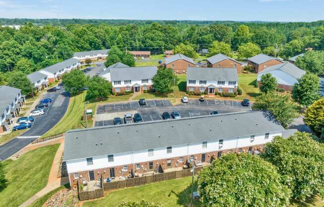 an aerial view of a building with a yard and a parking lot